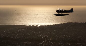 a seaplane flying at dusk with the san francisco coastline in the background