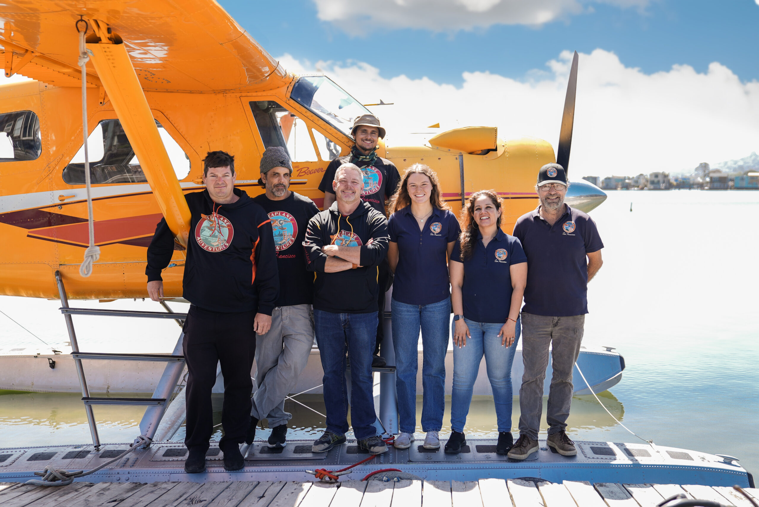 Employees of Seaplane Adventures smile in front of a yellow seaplane
