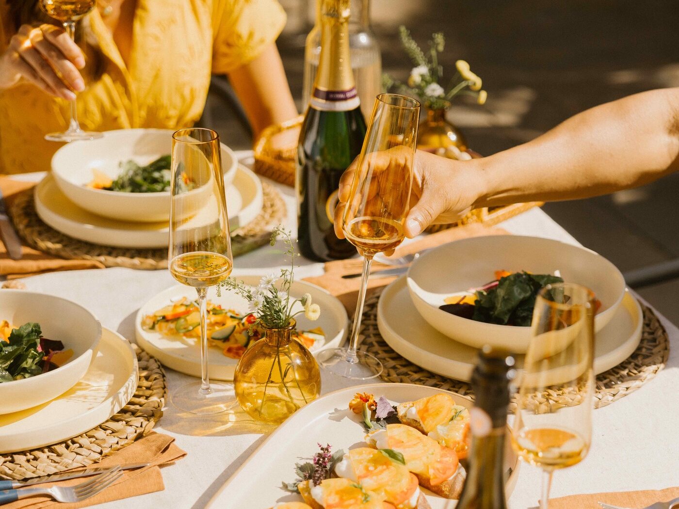 A person reaches for a champagne glass at a table of delicious food