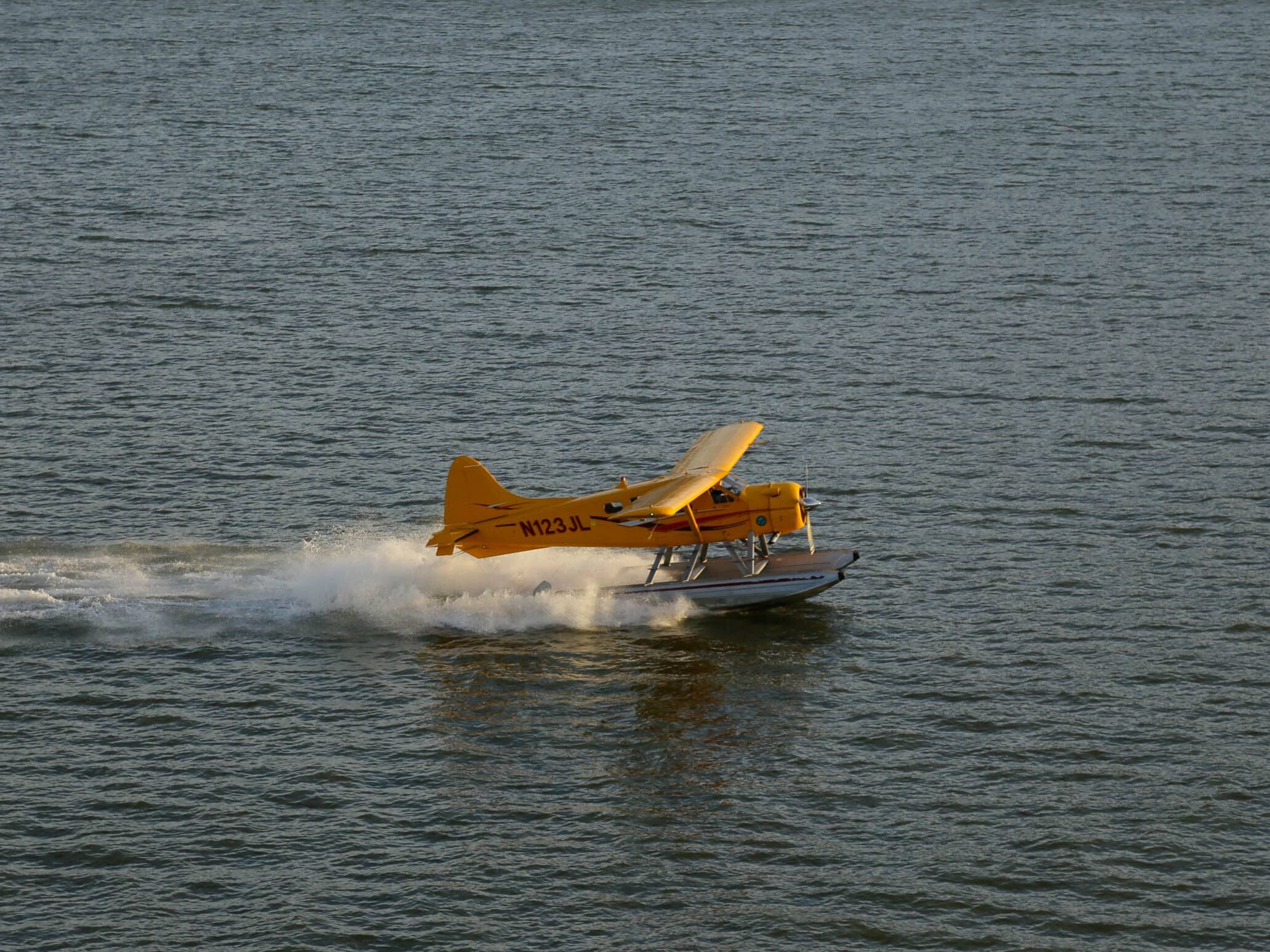 A yellow seaplane lands in the San Francisco Bay